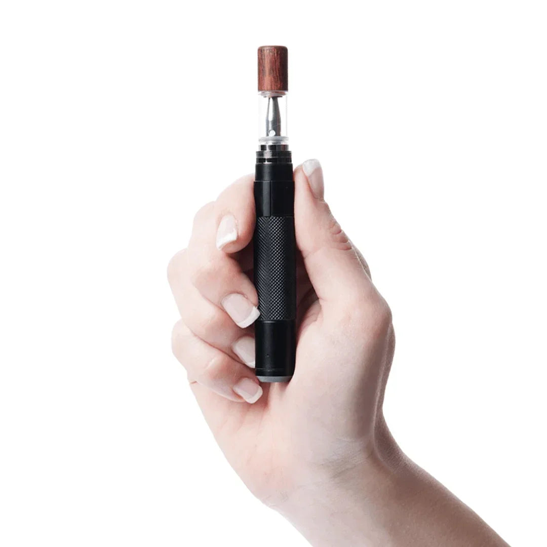 Hand holding a black portable vaporizer with wood mouthpiece on white background