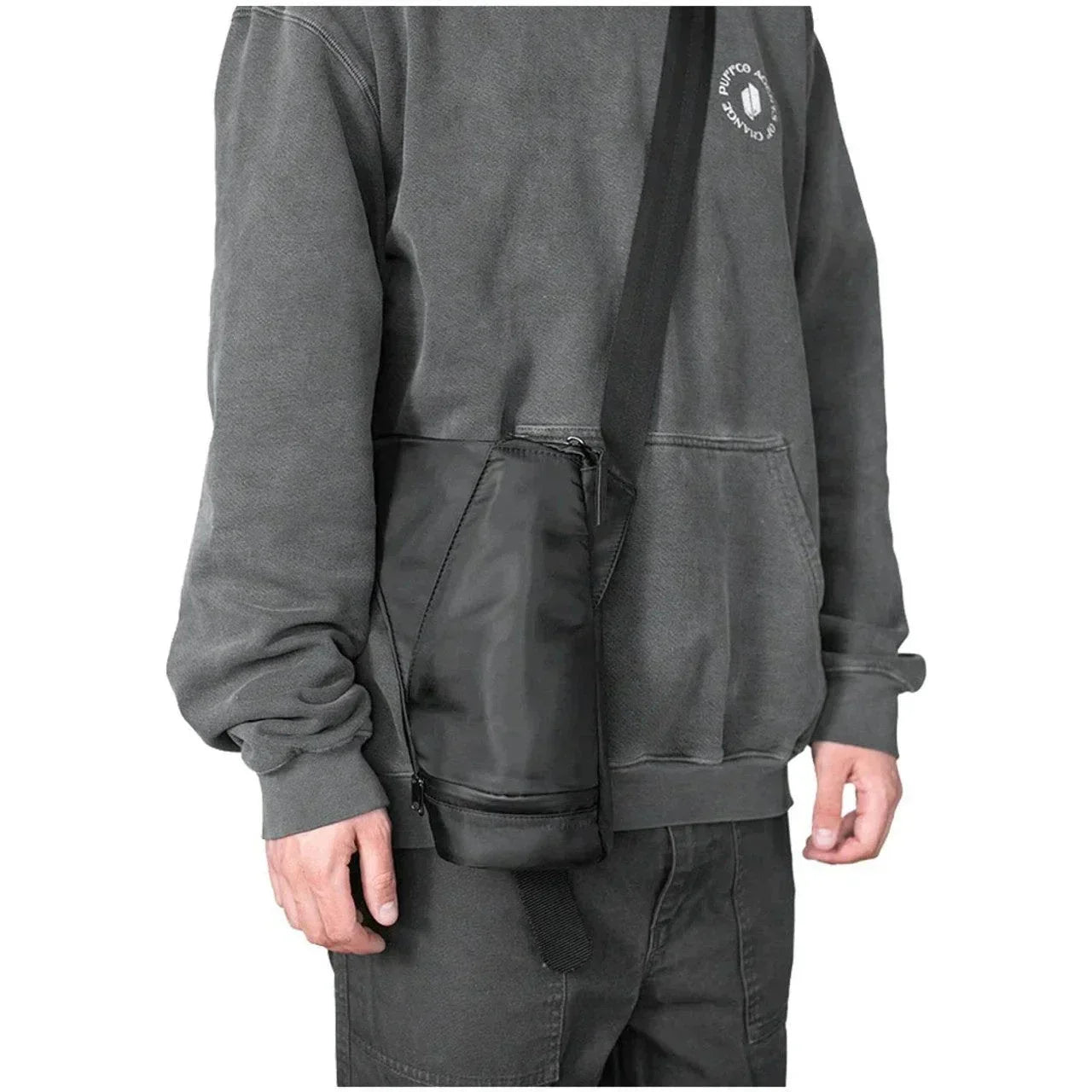 Person wearing a black crossbody bag shaped like a glass water pipe, casual streetwear style