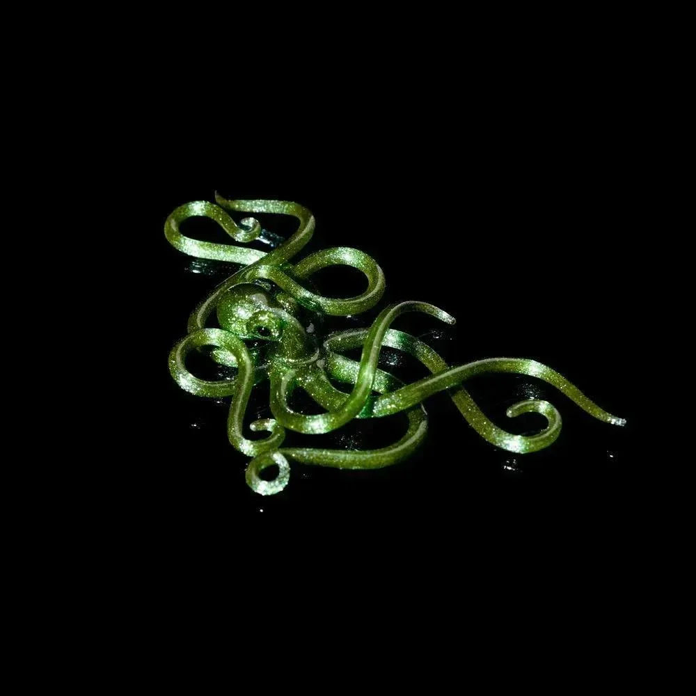 Green glass octopus sculpture with swirling tentacles on black background