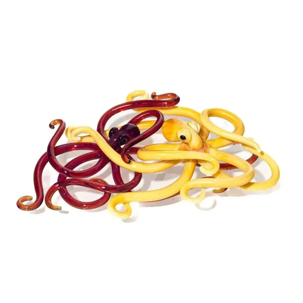 Handcrafted glass octopus figurines in yellow and red on a white background