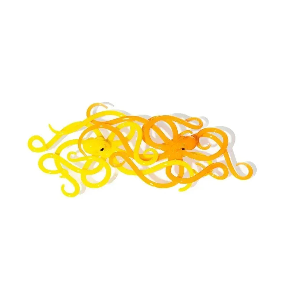 Yellow glass octopus figurines with swirling tentacles on white background