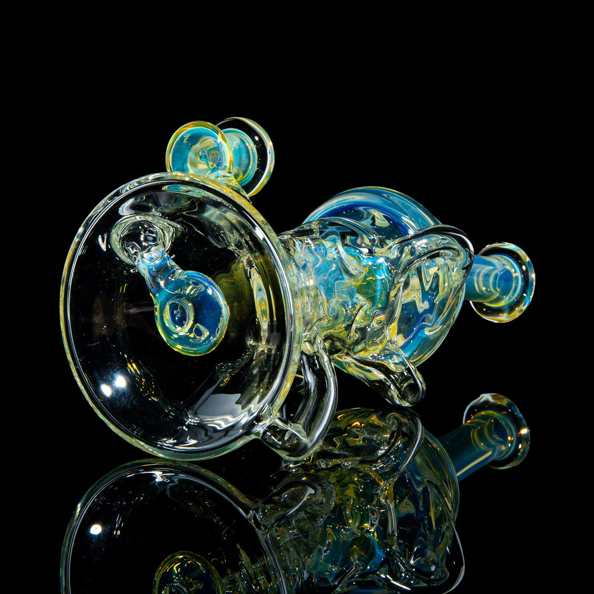 Heady glass water pipe with blue and yellow accents on a black reflective surface