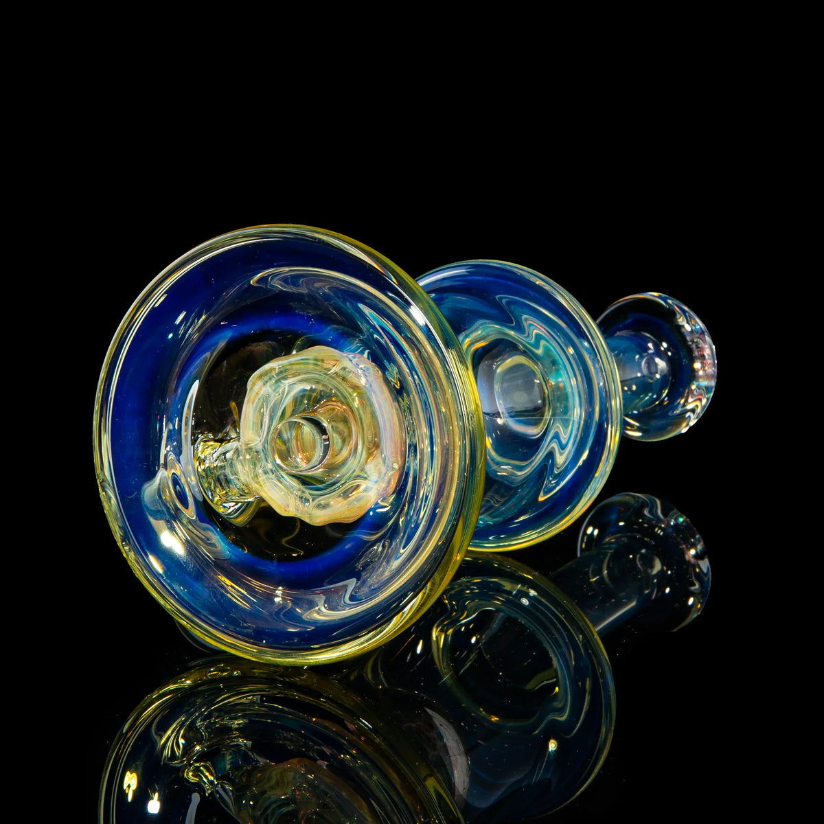Colorful hand-blown glass pipe with blue and yellow details on a black reflective surface