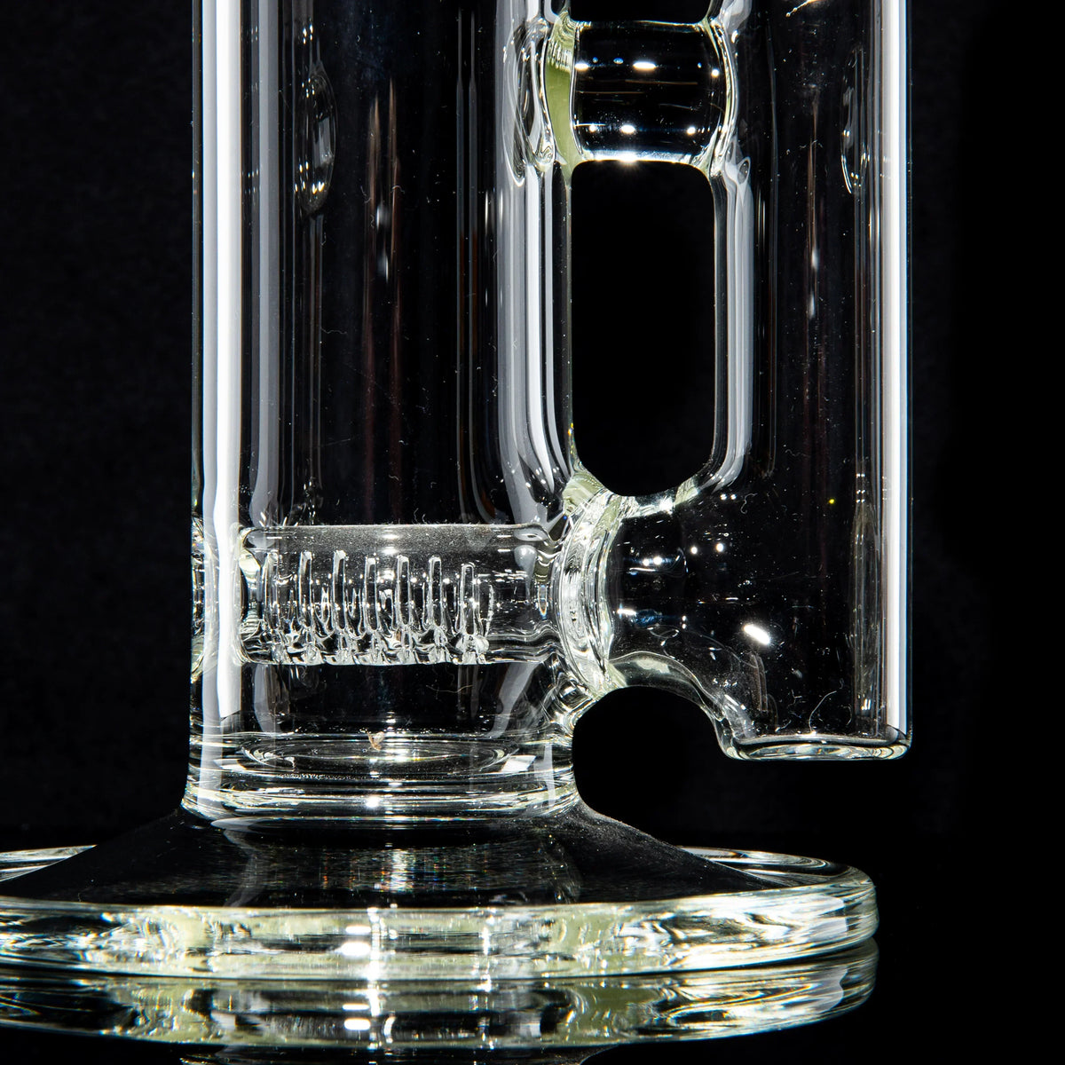 Close-up of a clear glass water pipe with detailed percolator, on black background.