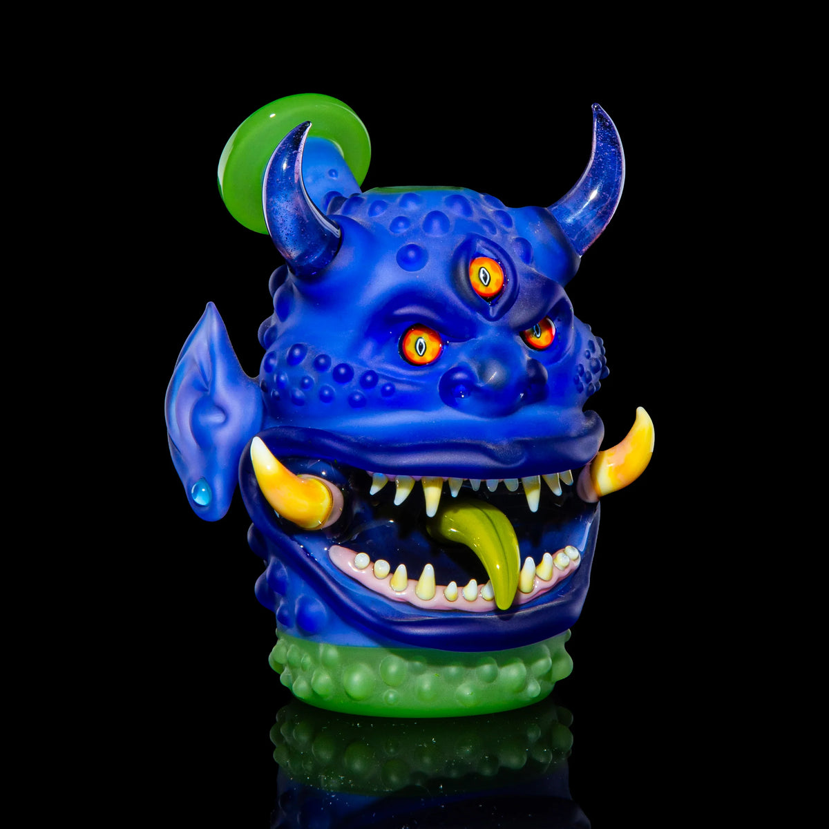 Heady glass pipe shaped like a blue monster with horns, tusks, three eyes, and a green tongue.