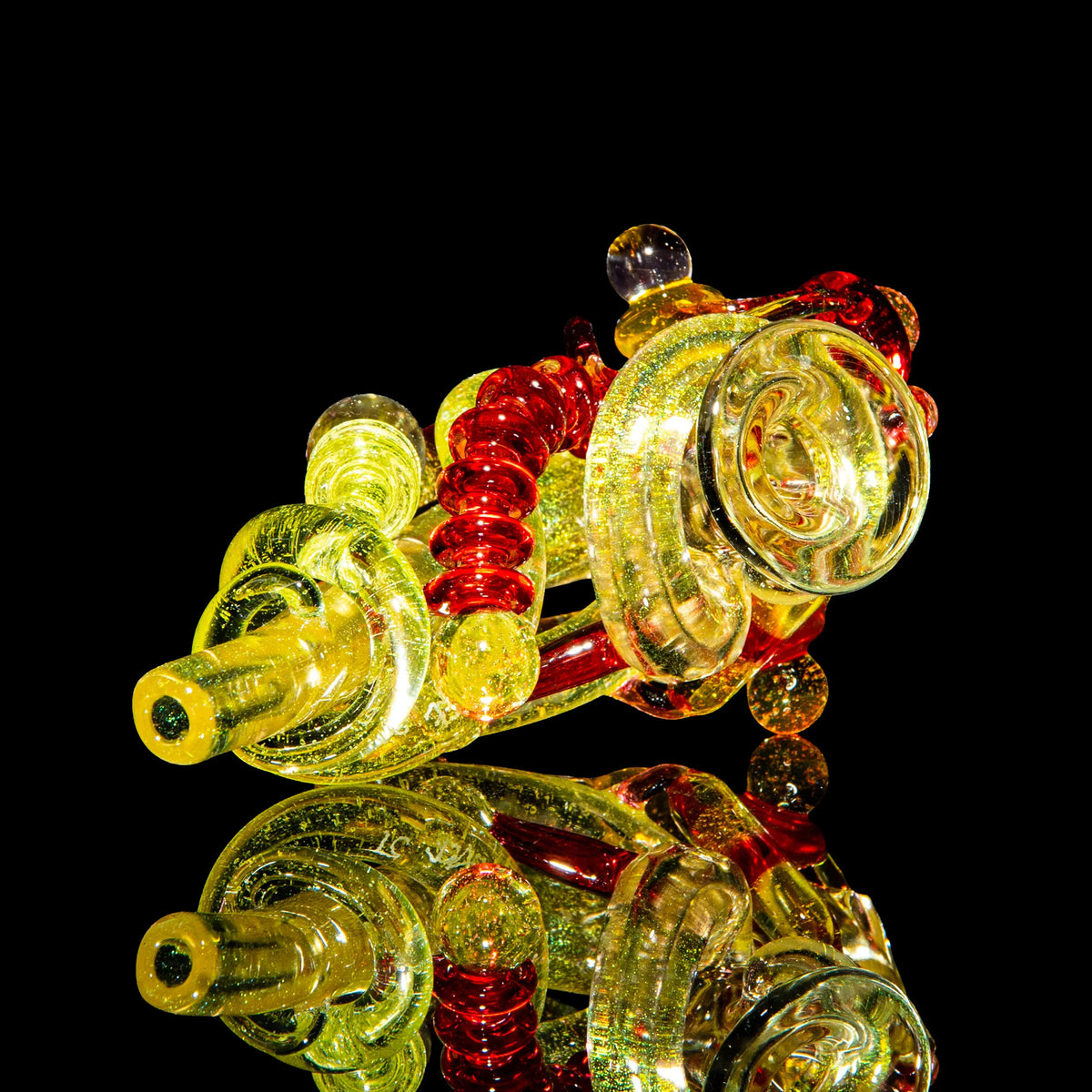 Heady glass smoking pipe with yellow and orange swirls on black background