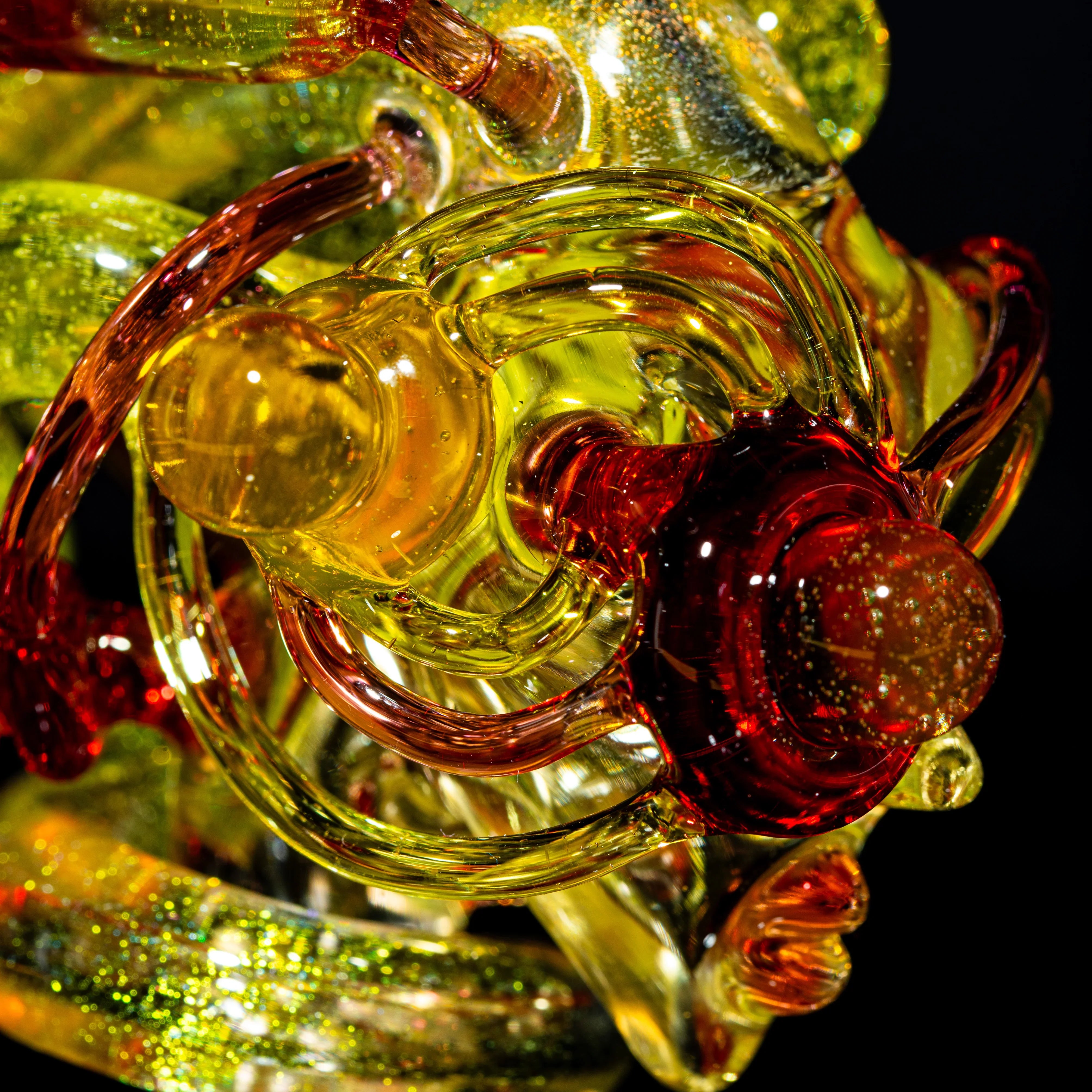 Close-up of intricate yellow and red heady glass art piece with sparkling details