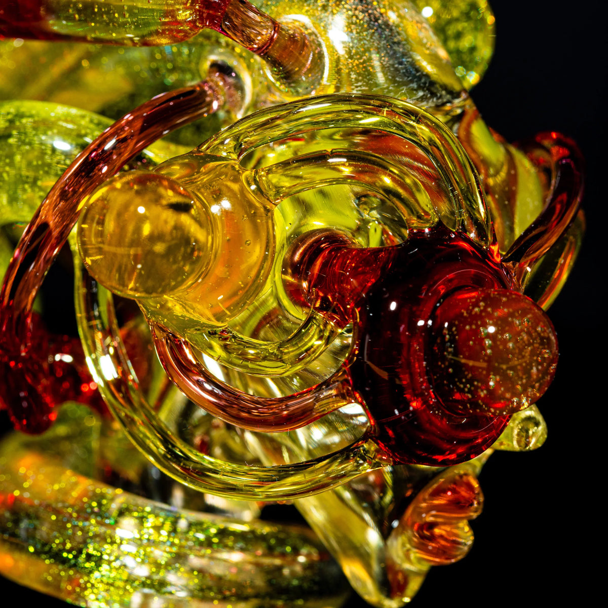 Close-up of intricate yellow and red heady glass art piece with sparkling details