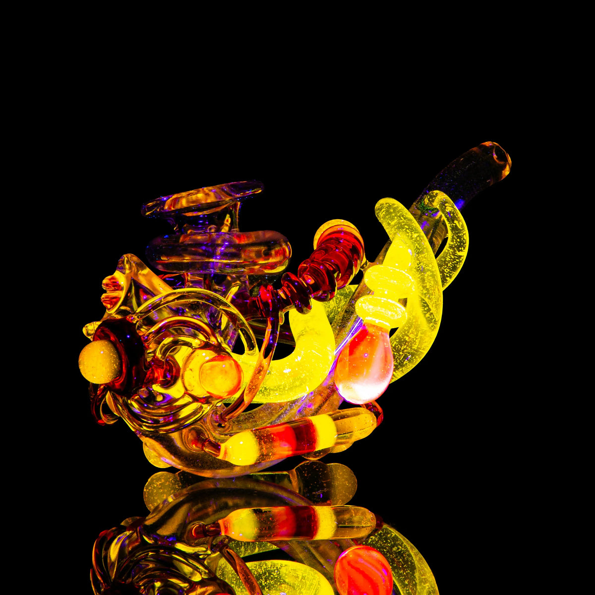 Colorful yellow and orange heady glass pipe with intricate design on black background