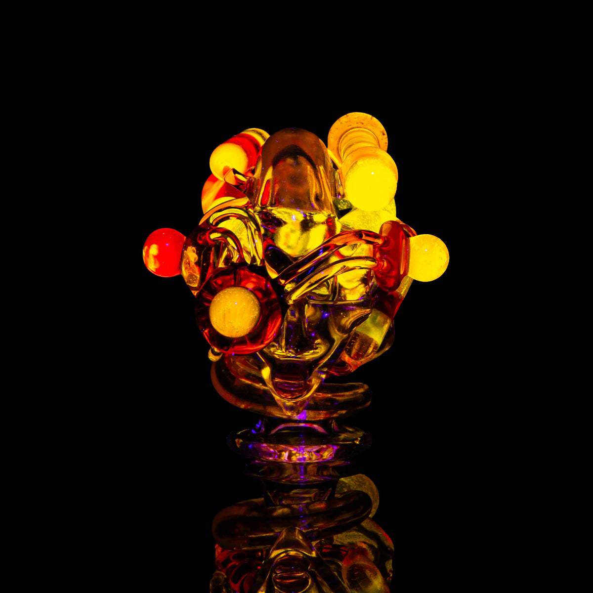 Heady glass sculpture with yellow and orange accents on a black background, art glass piece