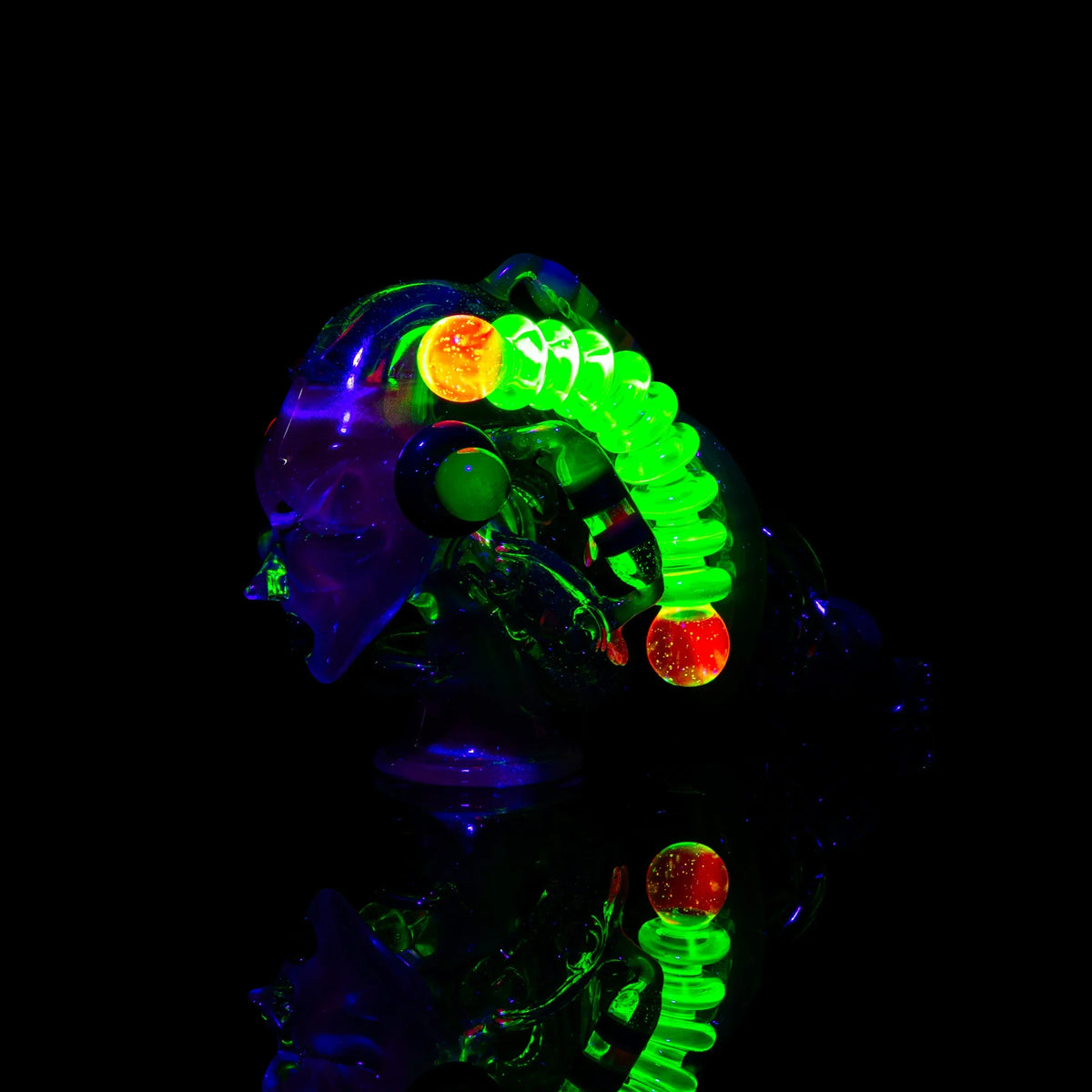 Heady glass art sculpture with glowing neon green coils and orange spherical accents