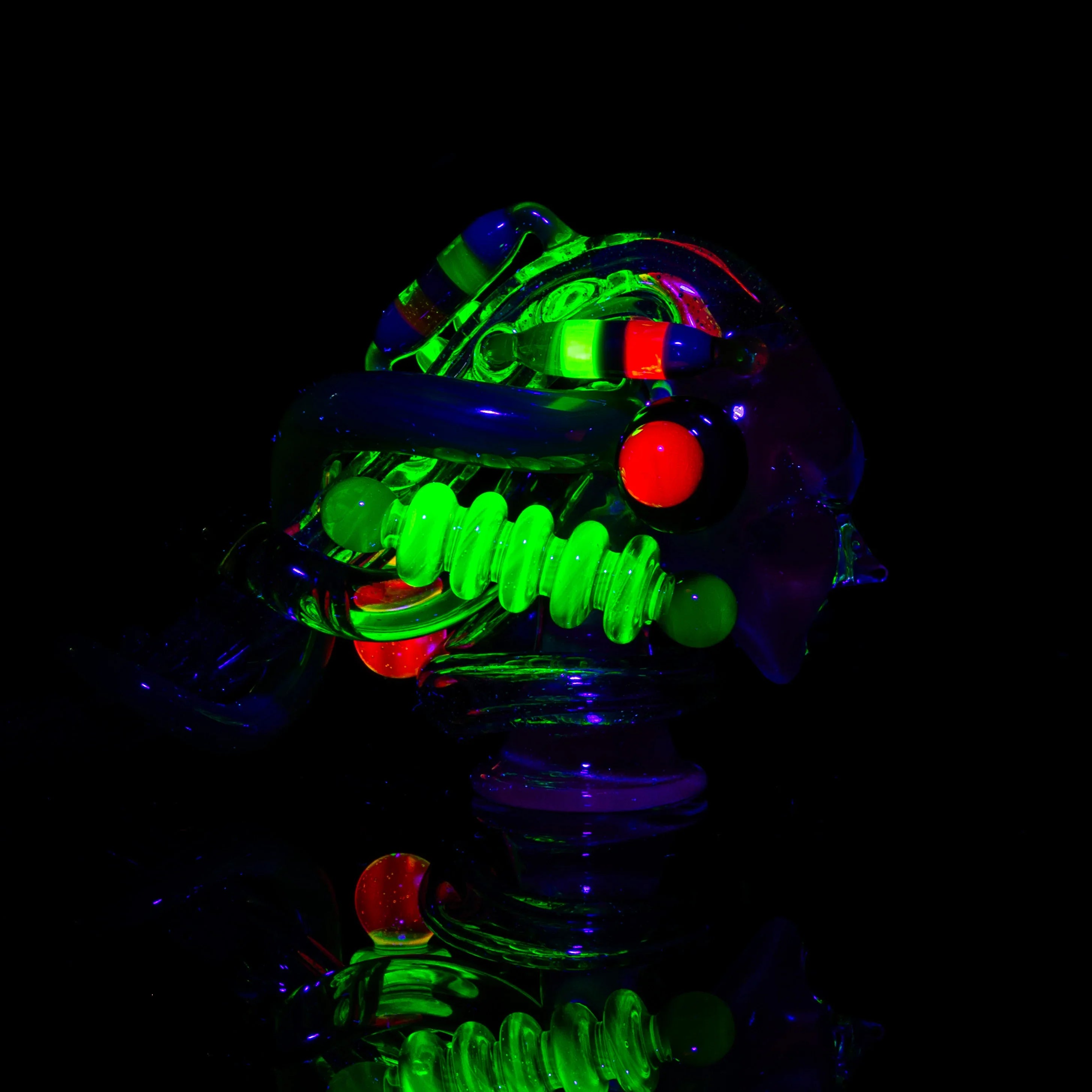 Heady glass pipe with blue, green, and red UV-reactive accents on black background