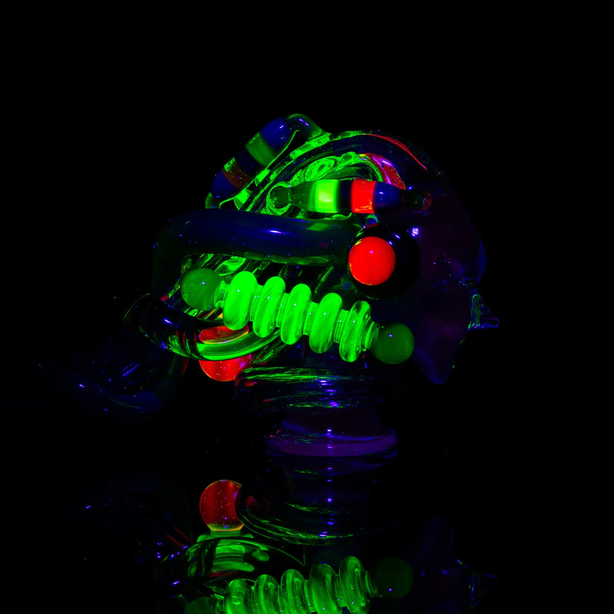 Heady glass pipe with blue, green, and red UV-reactive accents on black background