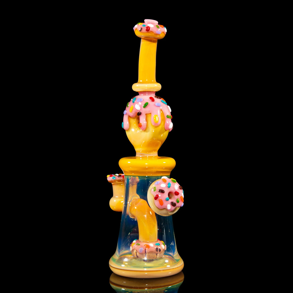 Heady glass water pipe with yellow and pink donut design, colorful sprinkles, on black background.