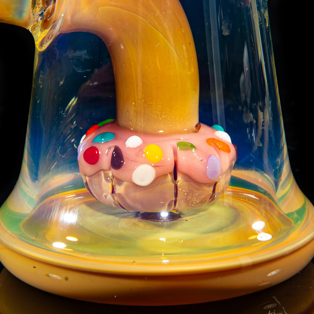Close-up of a handblown glass water pipe with a colorful donut-shaped accent base.