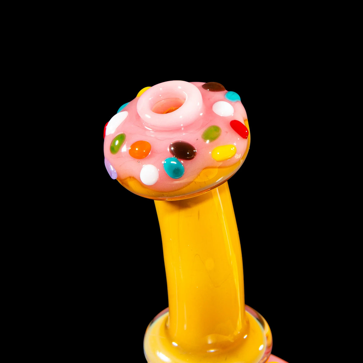 Colorful donut-themed glass pipe with pink frosting and candy sprinkles on black background