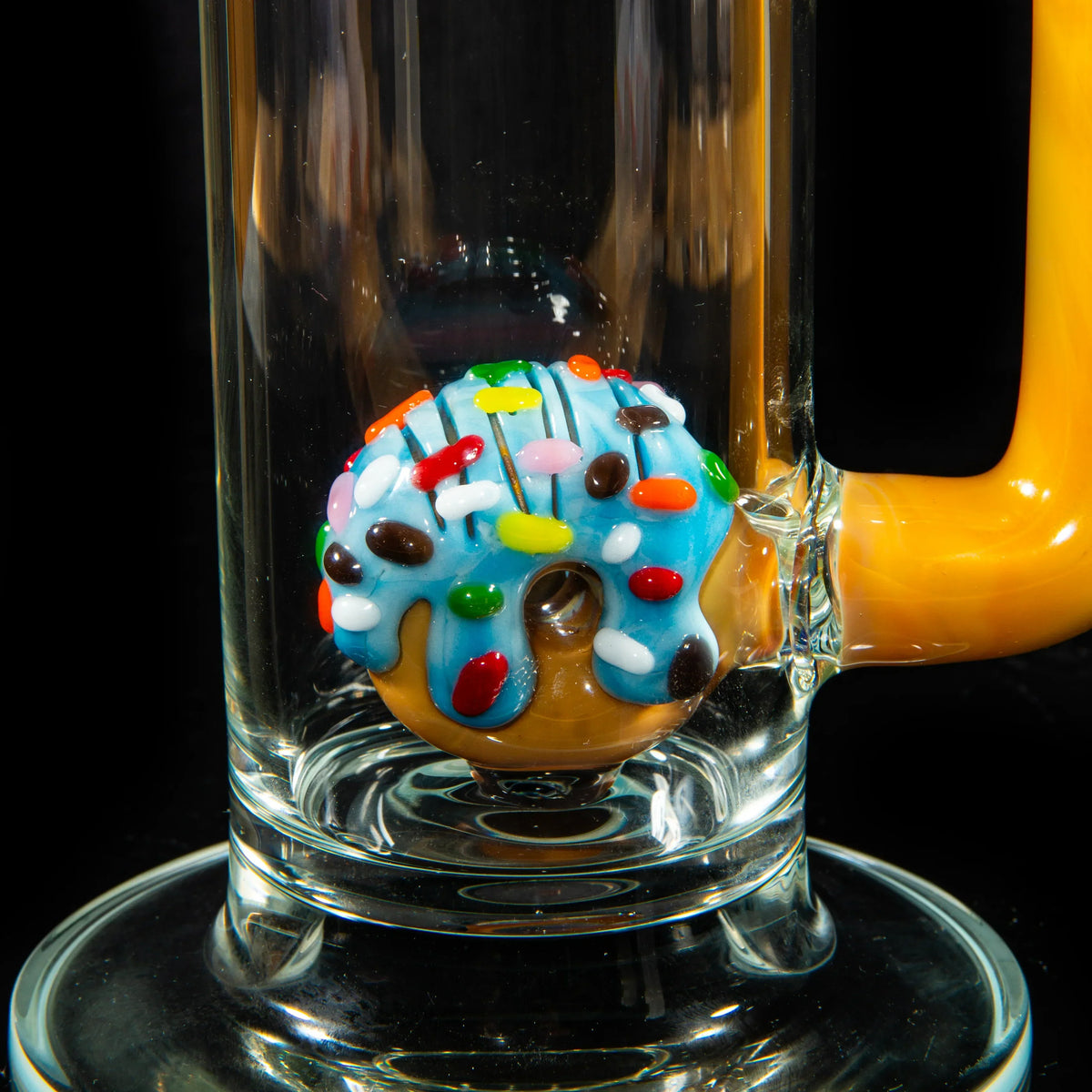 Close-up of a donut-themed glass percolator inside a water pipe with yellow accents