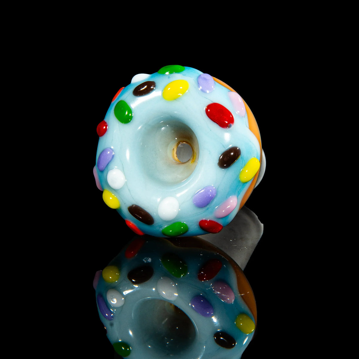 Hand-blown glass carb cap shaped like a donut with colorful sprinkles on a black background.