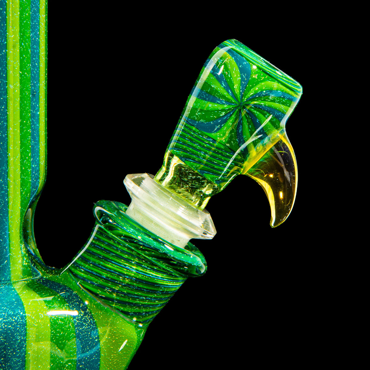 Close-up of a green and yellow heady glass bong with intricate swirl design on black background