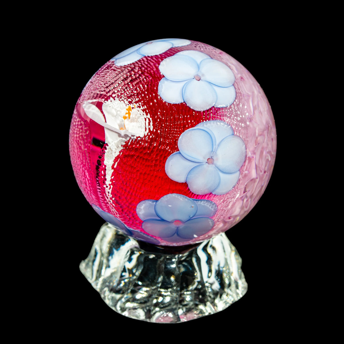 Hand-blown glass sphere with blue flower designs on a clear textured base, art glass decor.