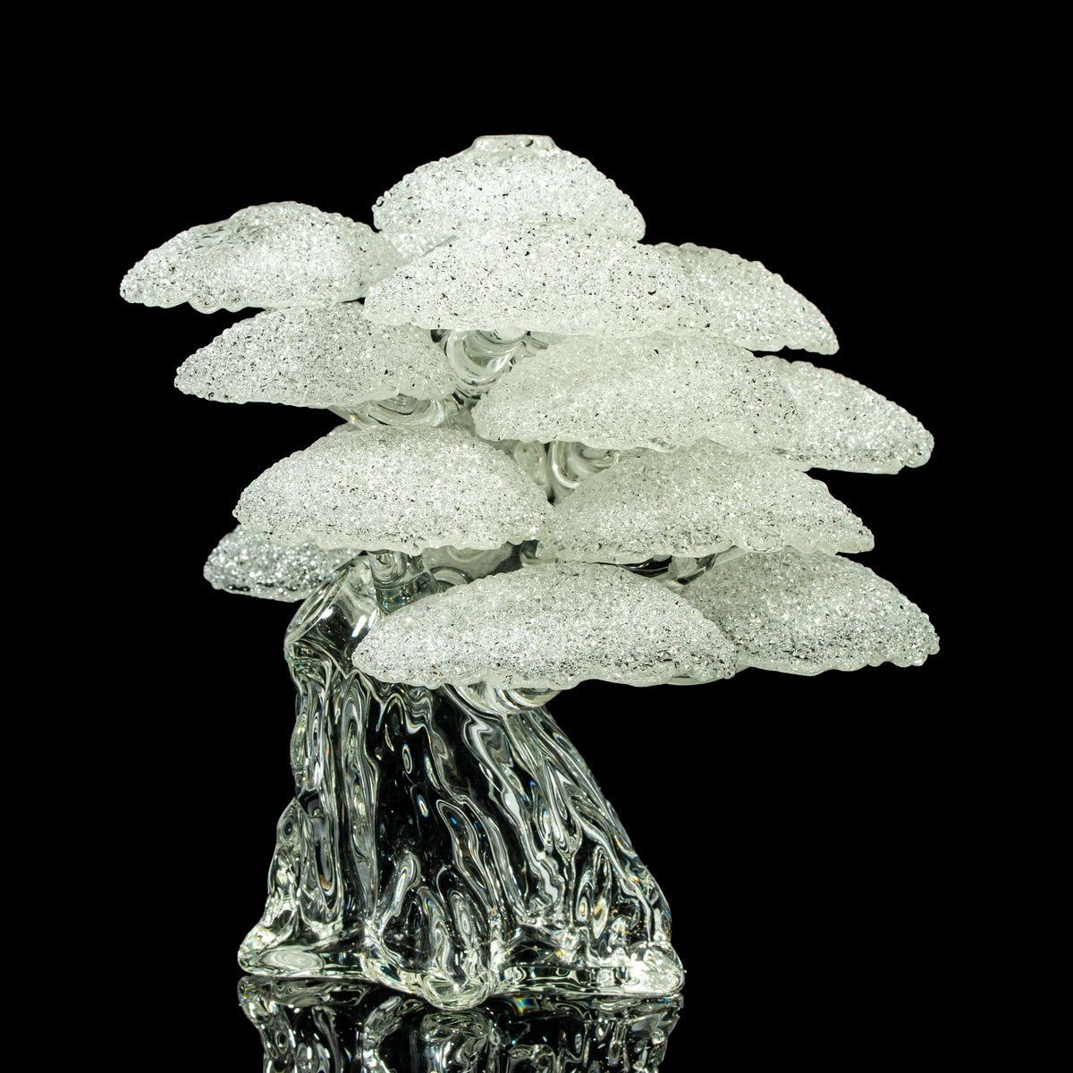 Clear textured glass sculpture resembling a tree with layered, frosted branches on black background