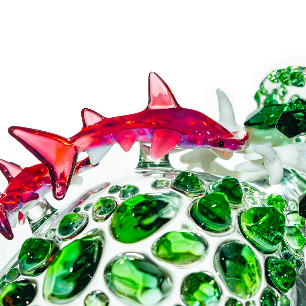 Handcrafted glass art featuring a red glass shark and green textured glass accents