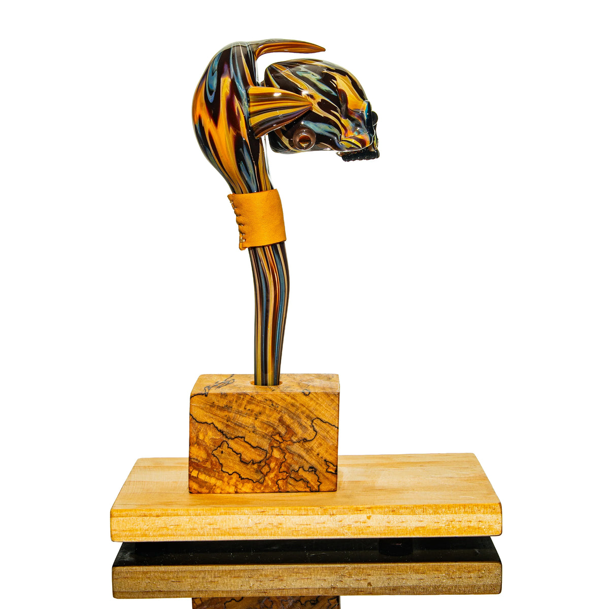 Handcrafted heady glass pipe with animal skull design on a wooden stand, colorful patterns