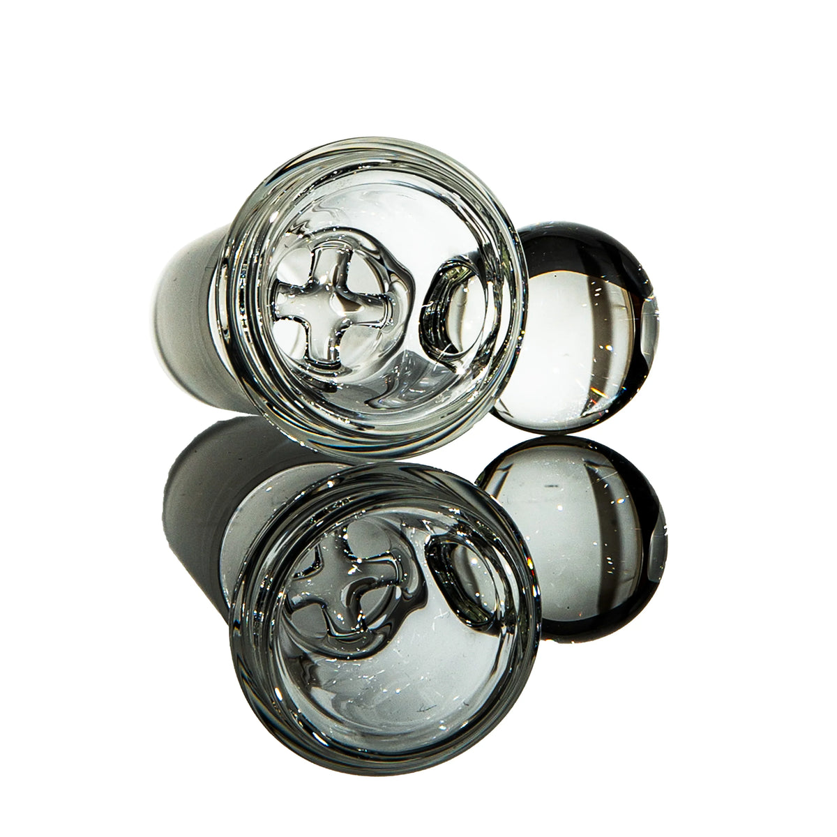 Clear glass carb cap with directional airflow design for concentrate rigs on reflective surface