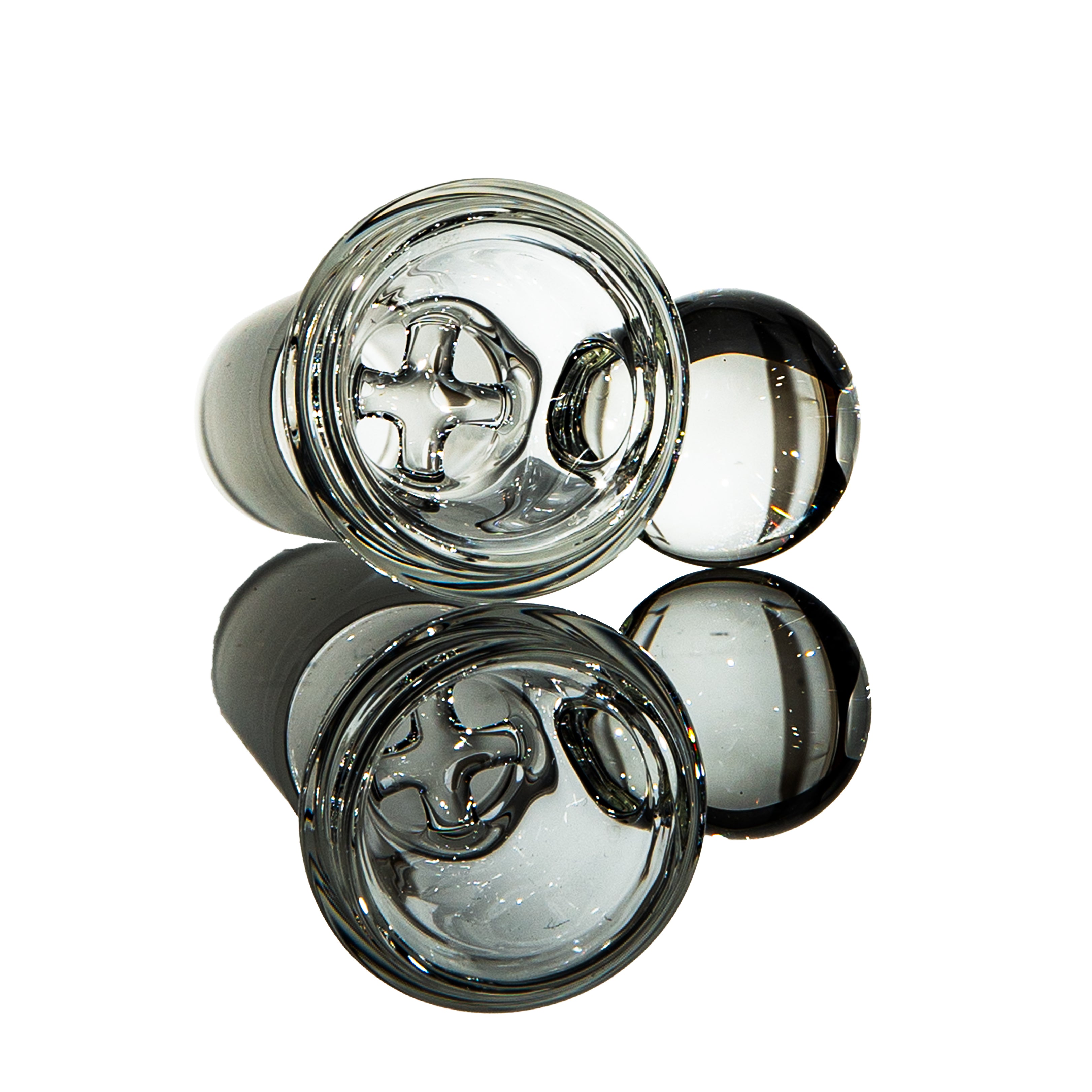 Clear glass carb cap with cross airflow design, smoking accessory on reflective surface