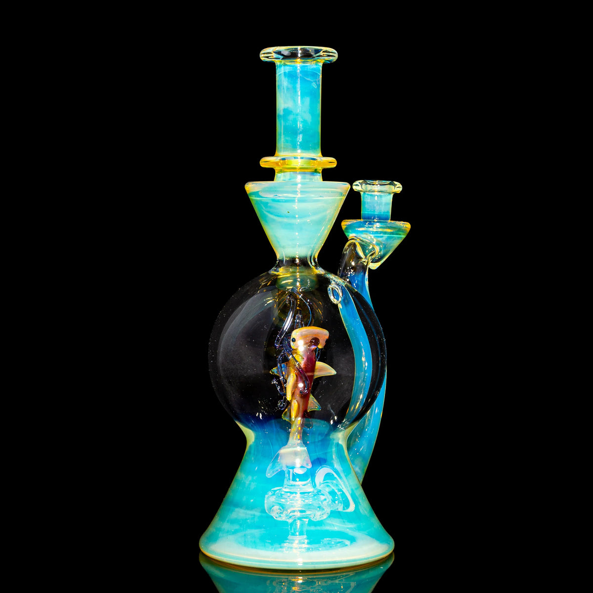 Heady artisan glass water pipe with blue accents and a sculpted fish inside, on black background.