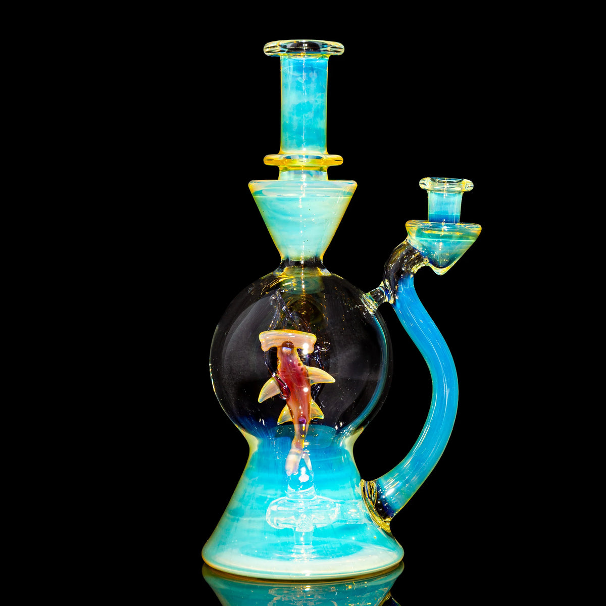 Artistic blue glass water pipe with a shark figurine inside, displayed on black background