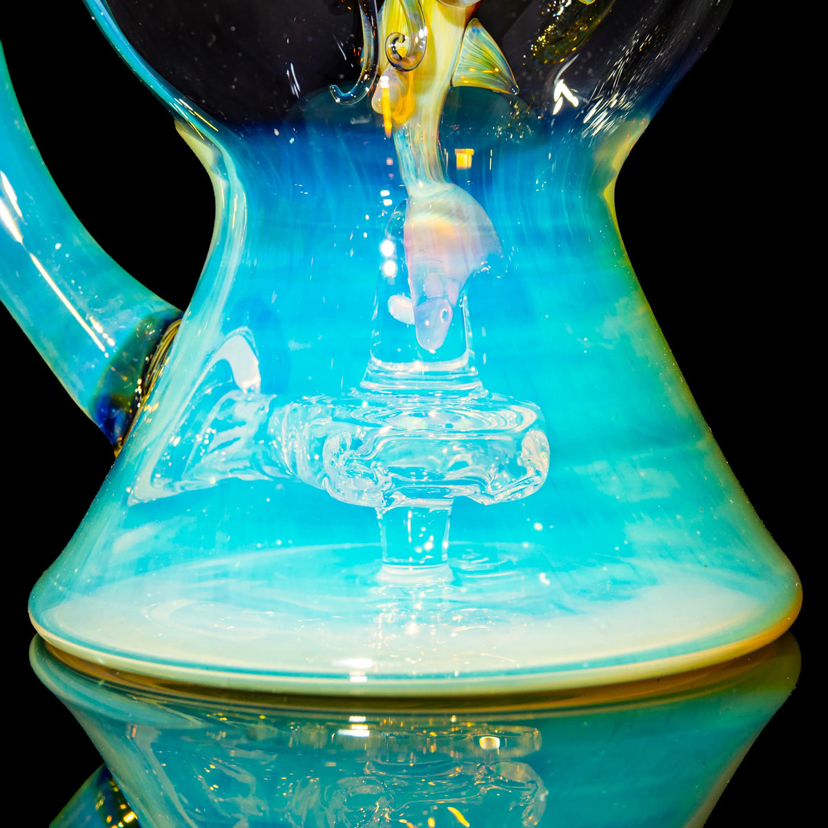 Close-up of an artistic blue glass water pipe with a fish design detail