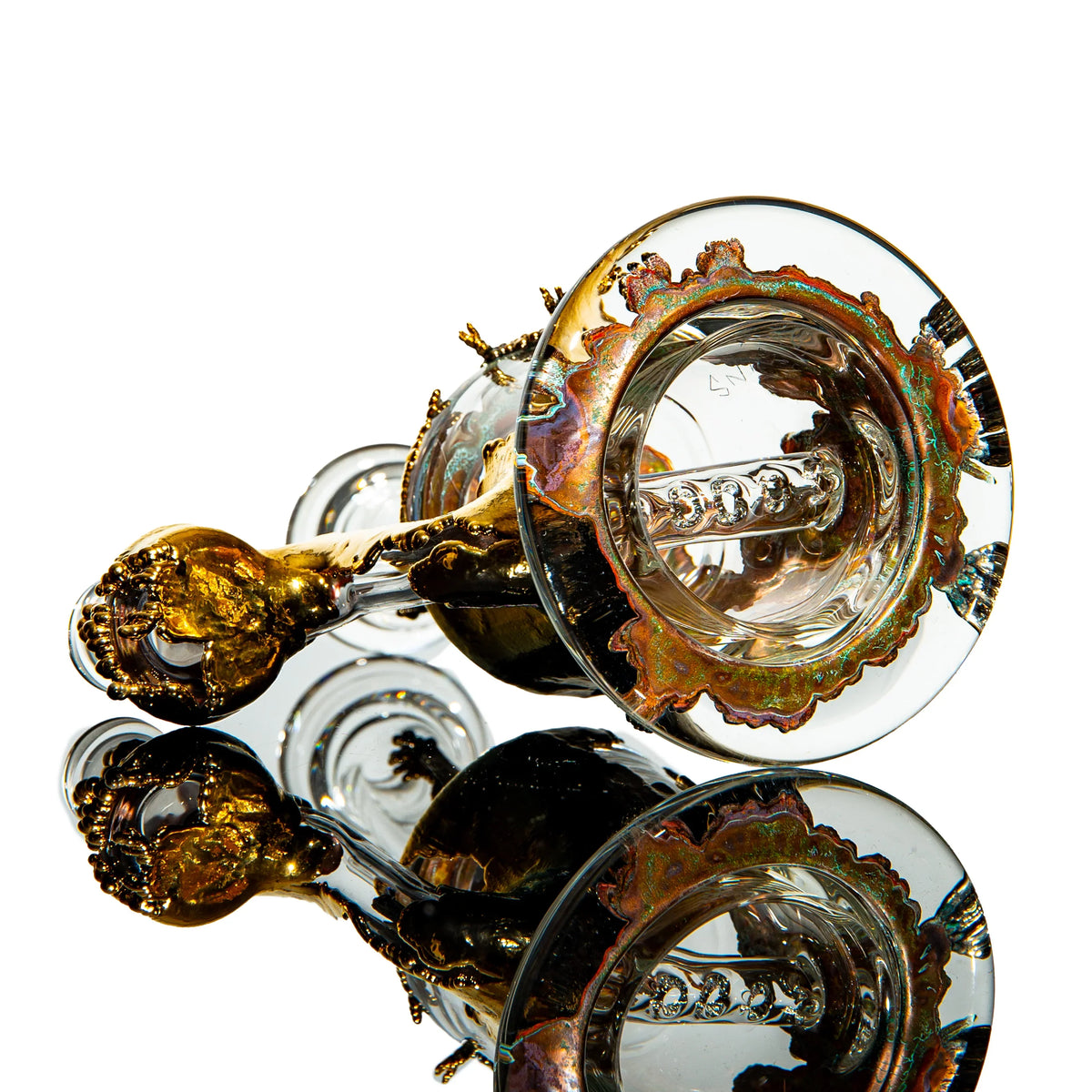 Heady glass water pipe with gold and iridescent accents on a reflective surface