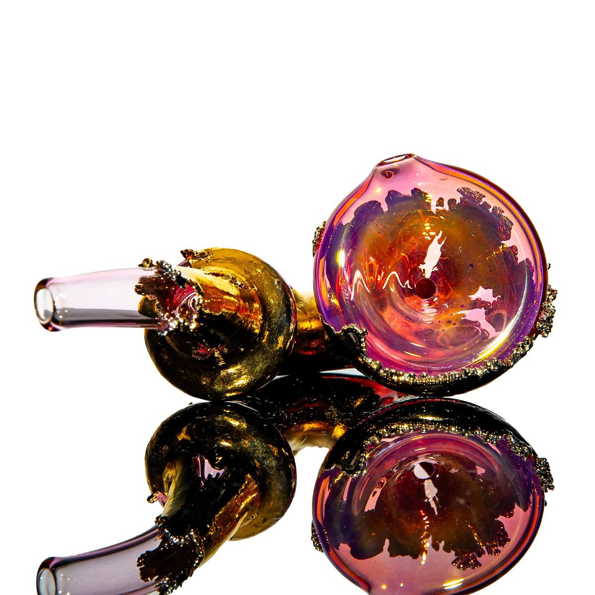 Colorful artisan glass hand pipe with gold and pink accents on reflective surface