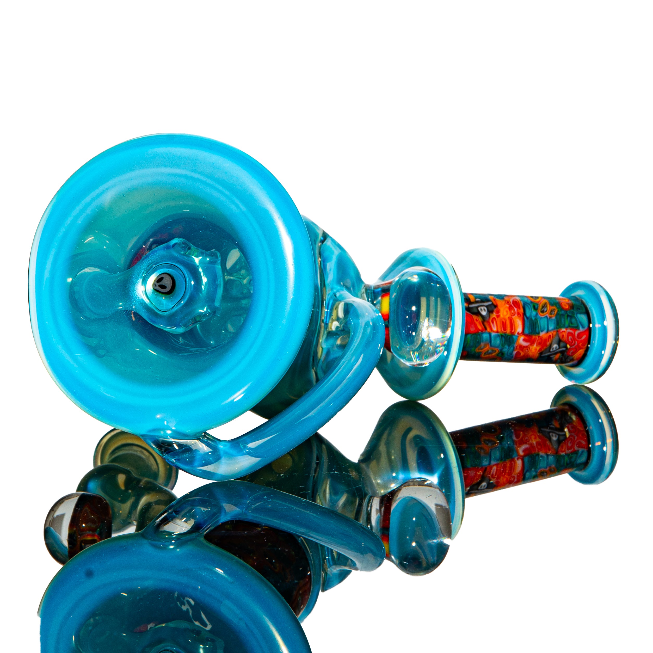 Blue glass hand pipe with vibrant millefiori patterns, shown on reflective surface