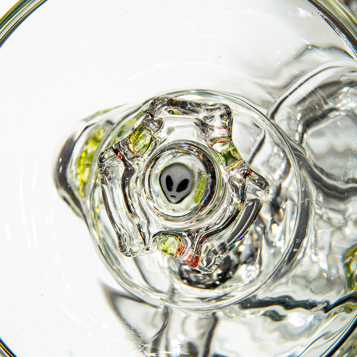 Close-up of clear glass pipe with alien face detail inside, artistic heady glass accessory