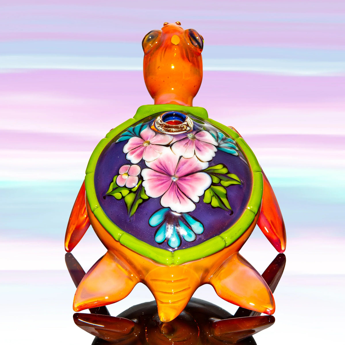 Colorful glass turtle pipe with floral design on shell against pastel background