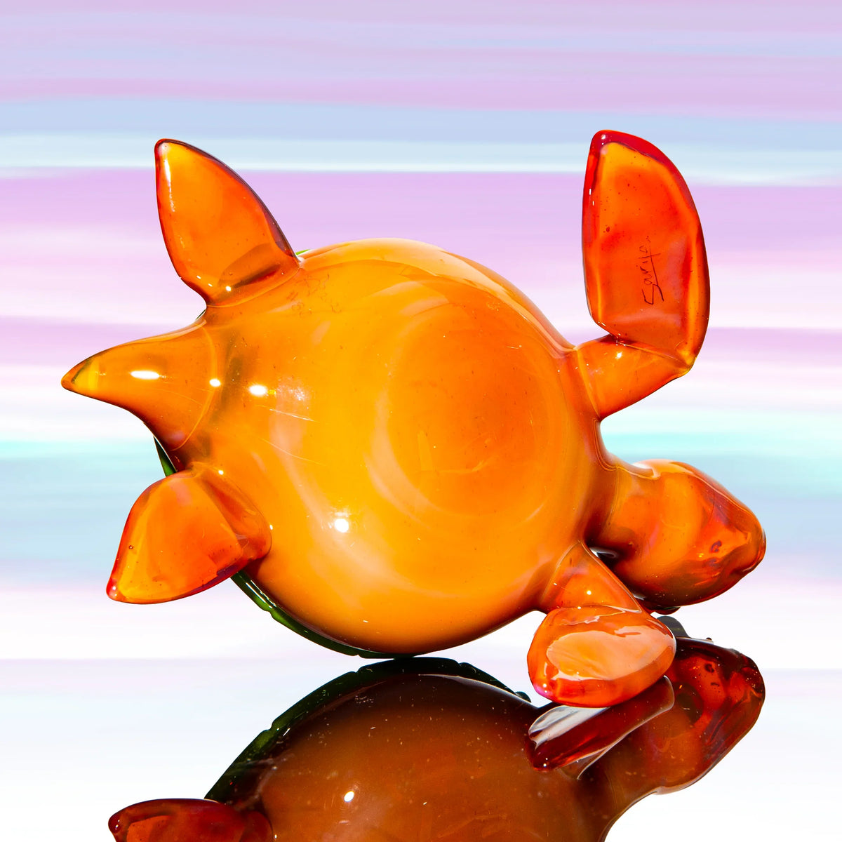 Hand-blown orange glass turtle figurine on pastel background, artistic smoking accessory