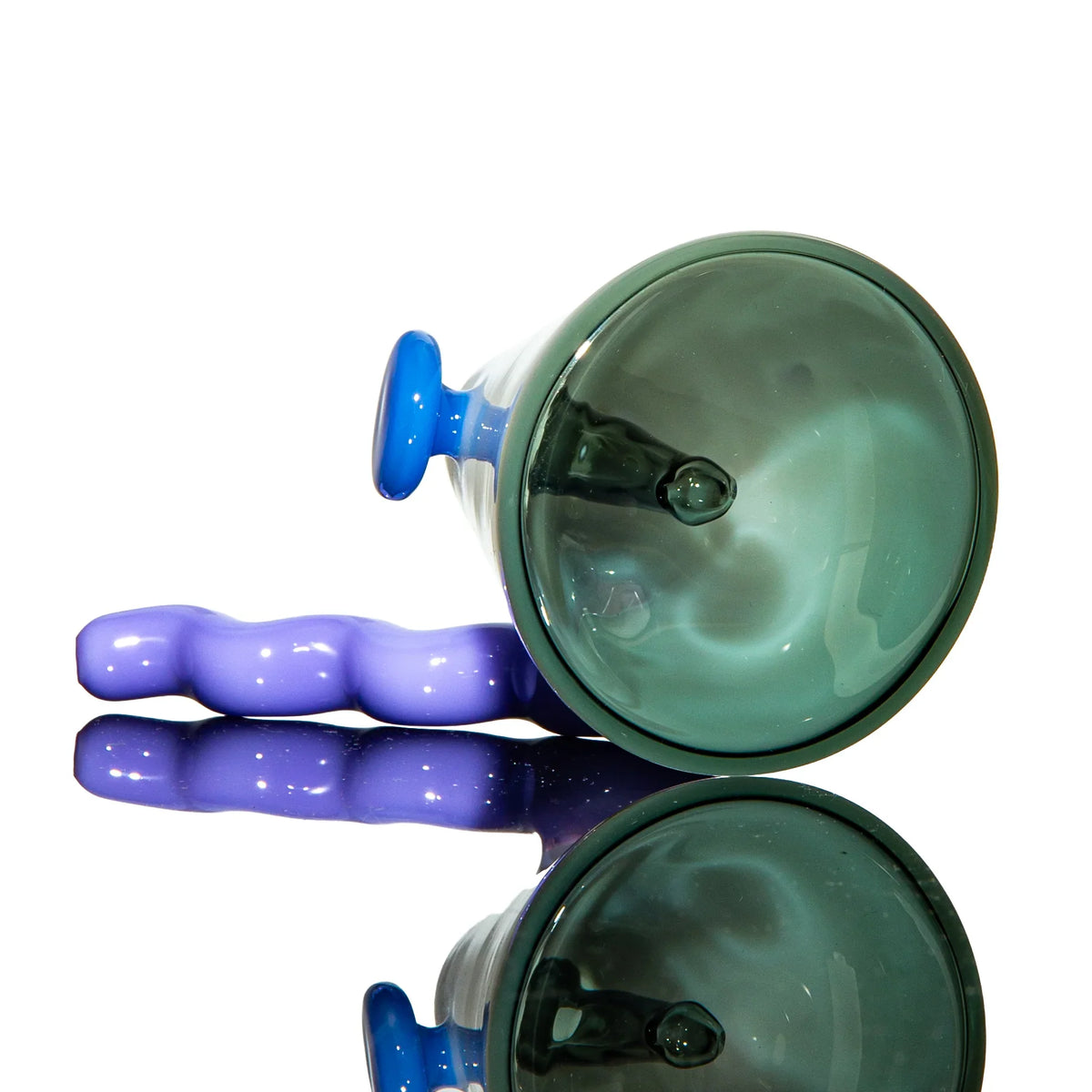 Hand-blown glass pipe with wavy lavender handle and teal bowl on reflective surface