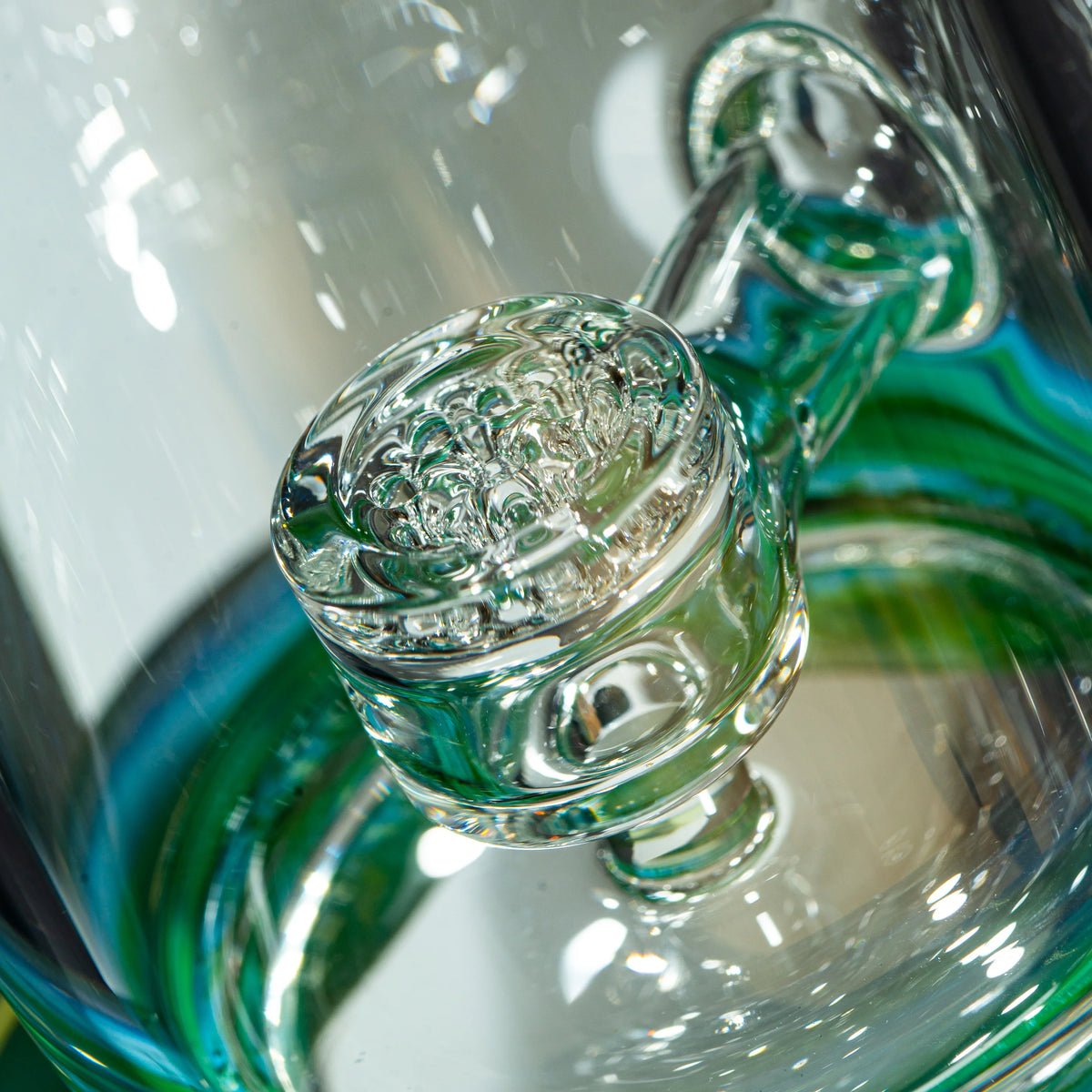 Close-up of intricate glass water pipe percolator with green accents