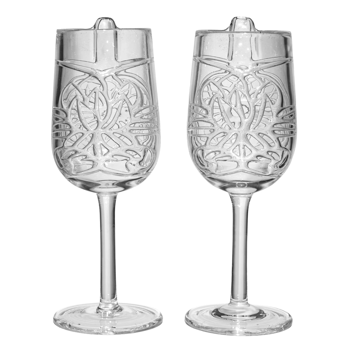 Pair of clear, intricately designed glass goblets with artistic patterns and long stems