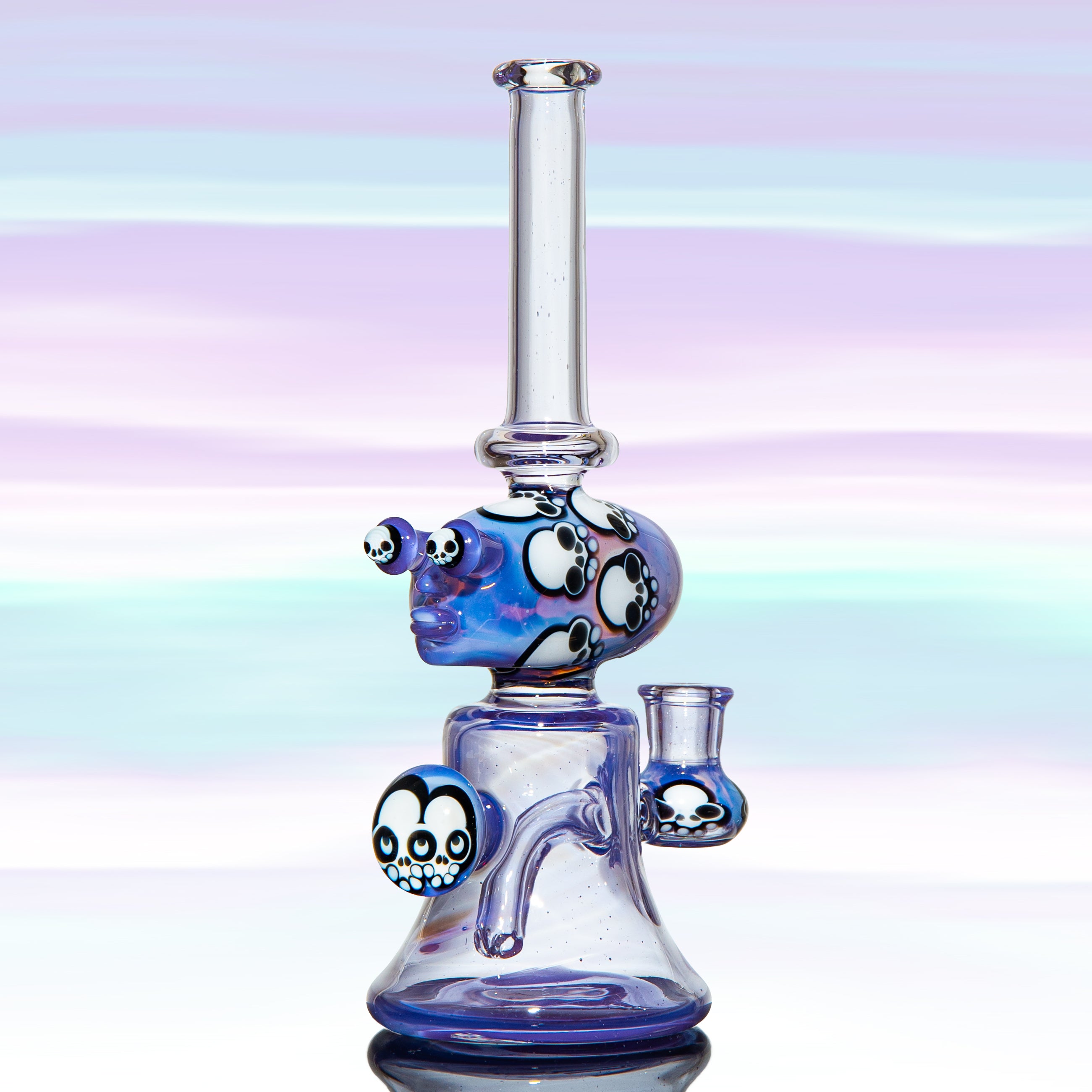 Heady glass water pipe with skull designs on a pastel gradient background