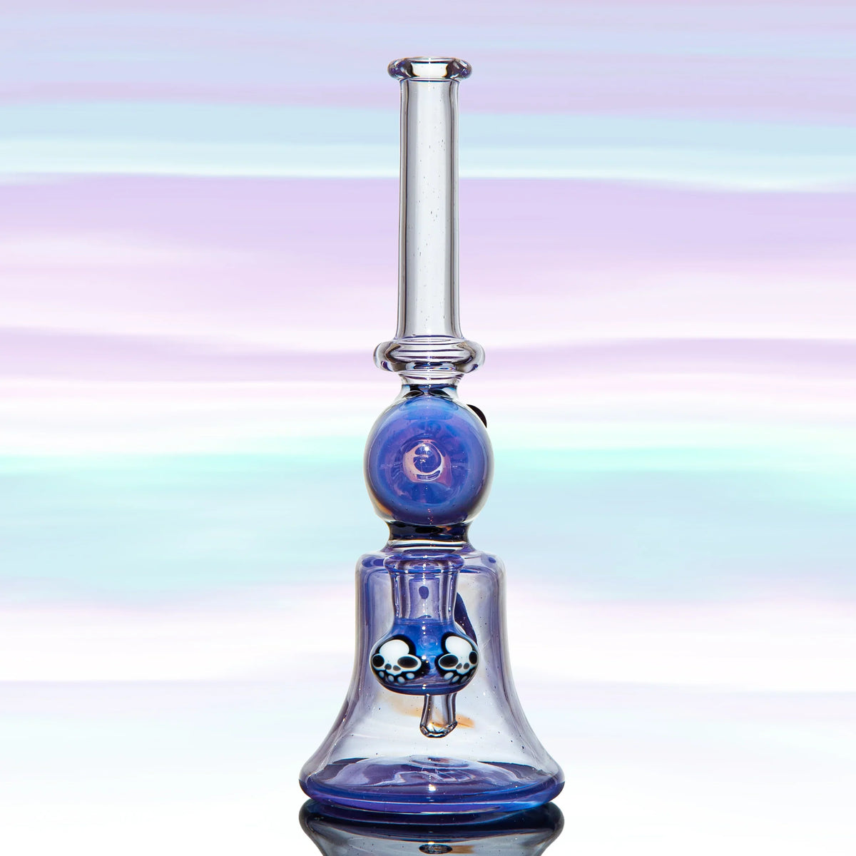 Blue heady glass water pipe with skull accents on a pastel background