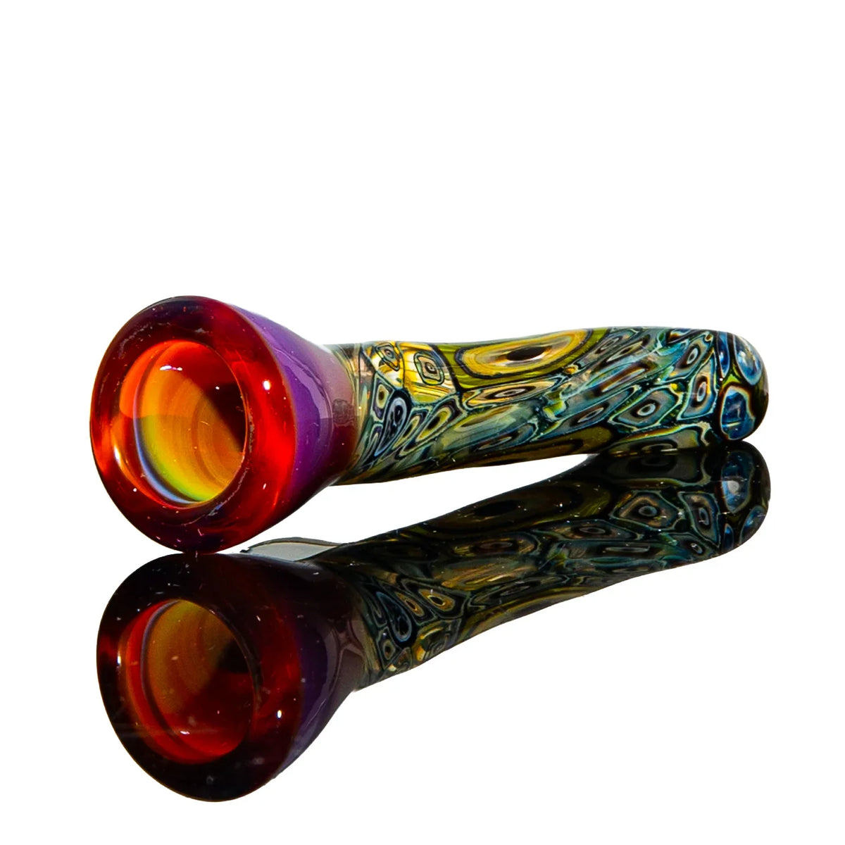 Colorful glass hand pipe with red bowl and intricate patterned stem, reflected on surface.