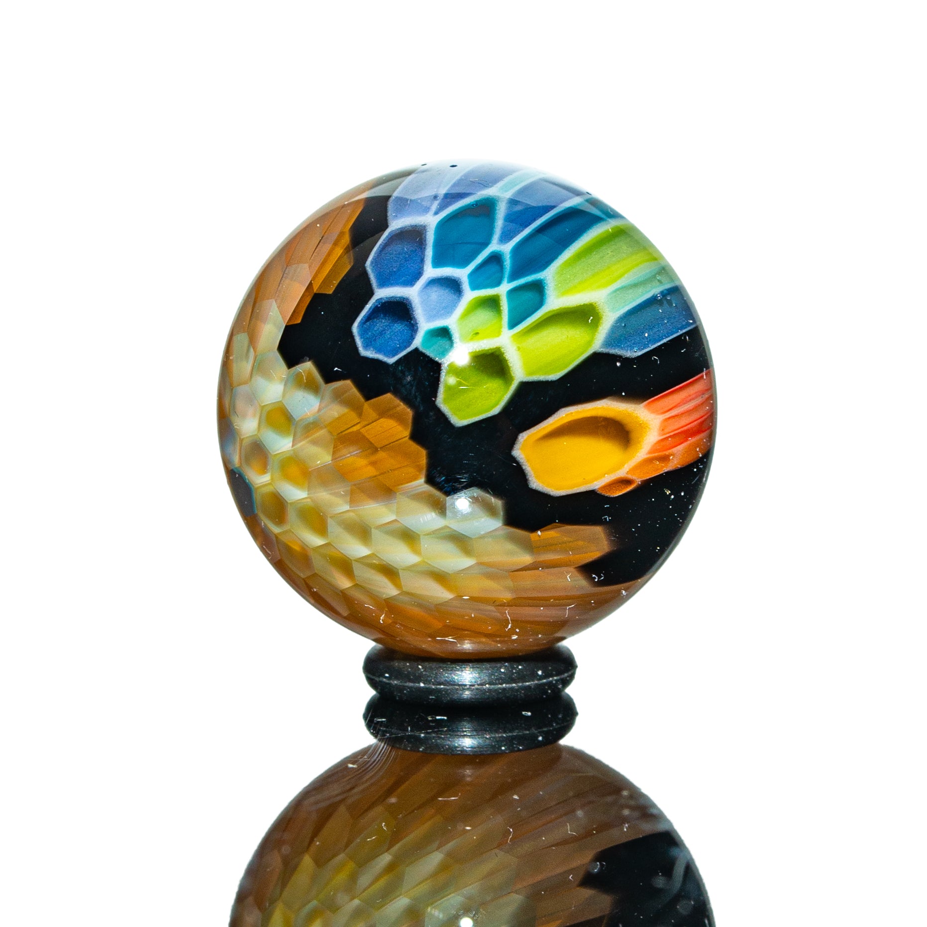 Colorful honeycomb-patterned glass marble with vibrant geometric designs on a black base