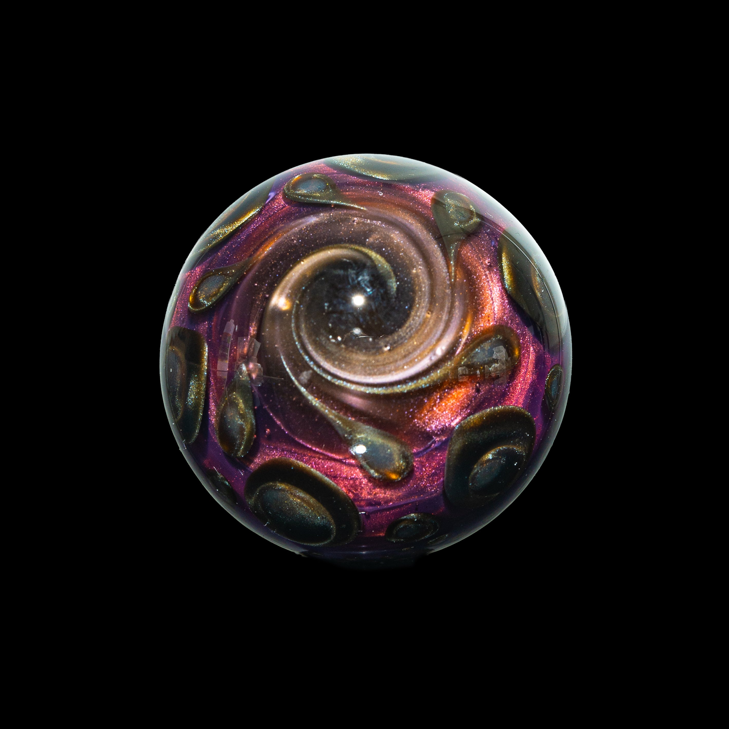 Handcrafted glass marble with metallic swirl and iridescent galaxy design on black background