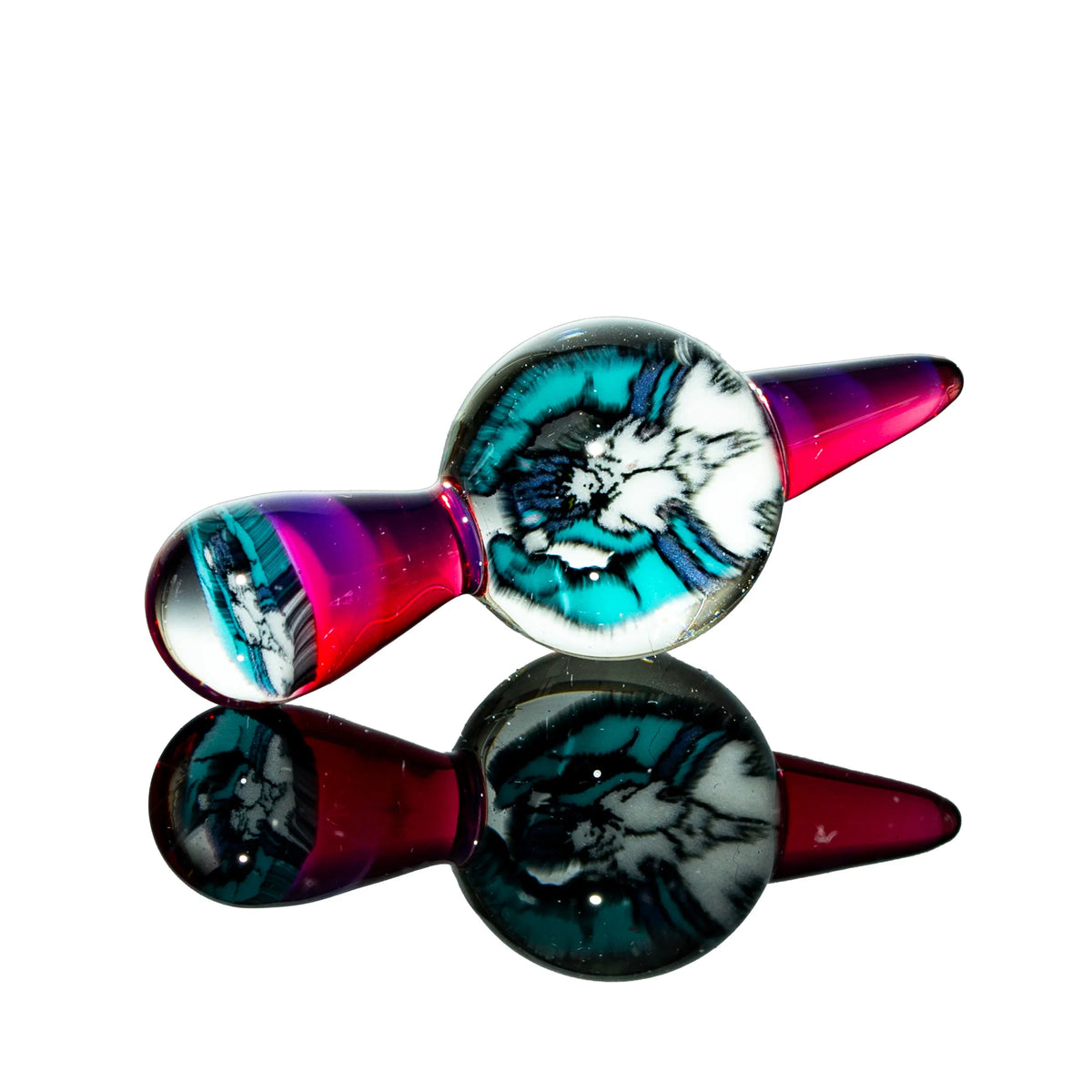 Colorful glass carb cap with teal, white, and black design on reflective surface