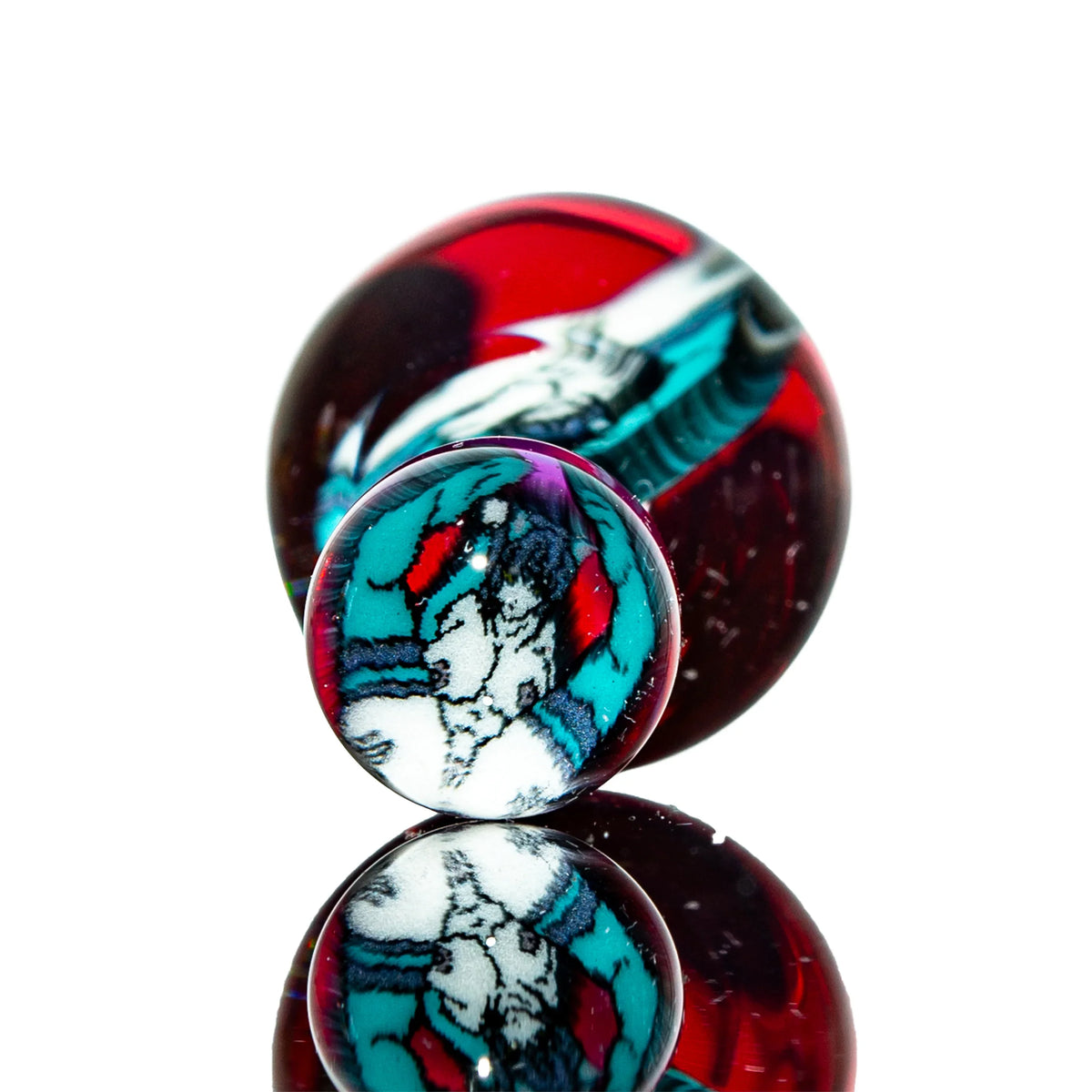 Colorful glass marble with teal, red, black, and white swirling patterns on reflective surface