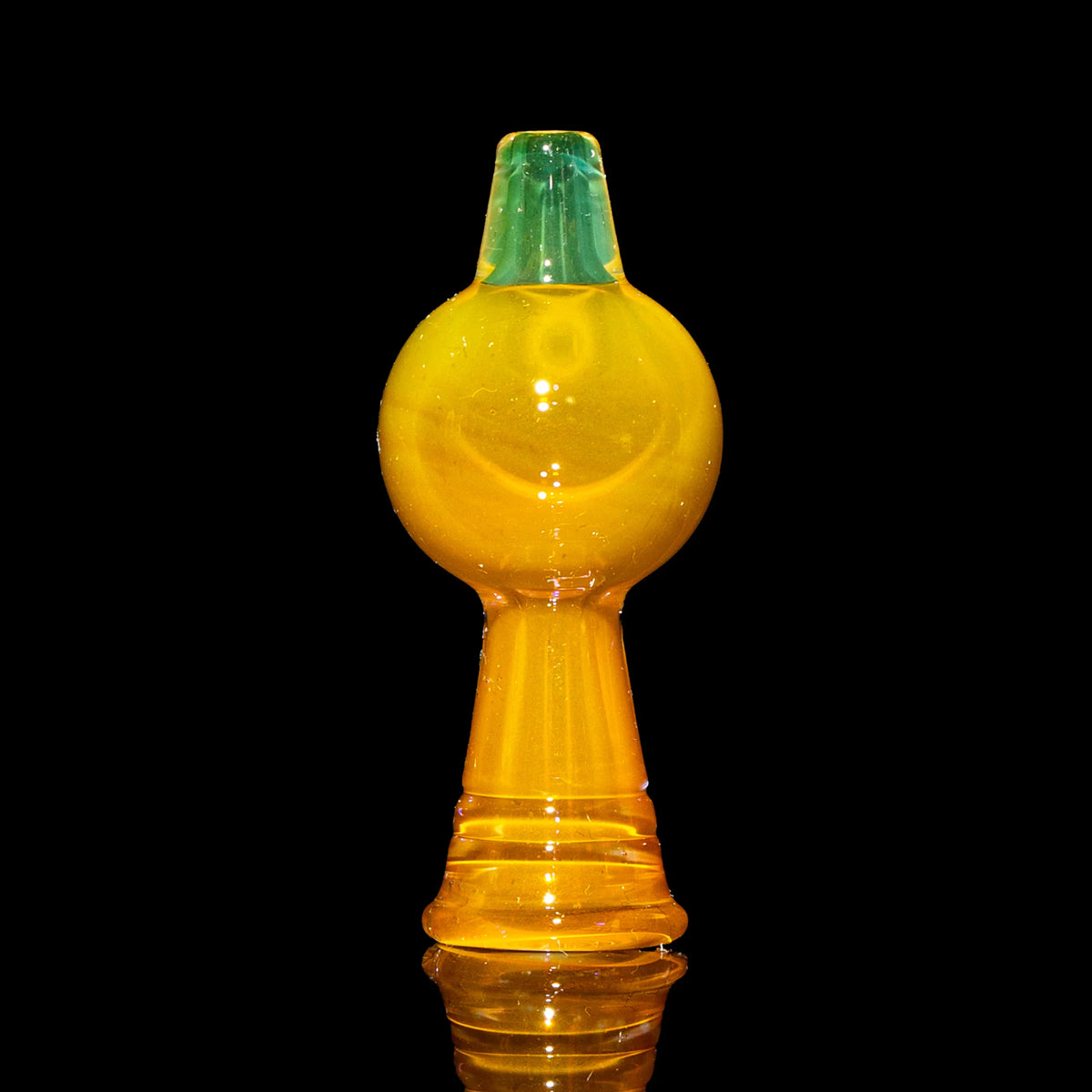 Yellow glass carb cap with teal top for dab rigs on black background