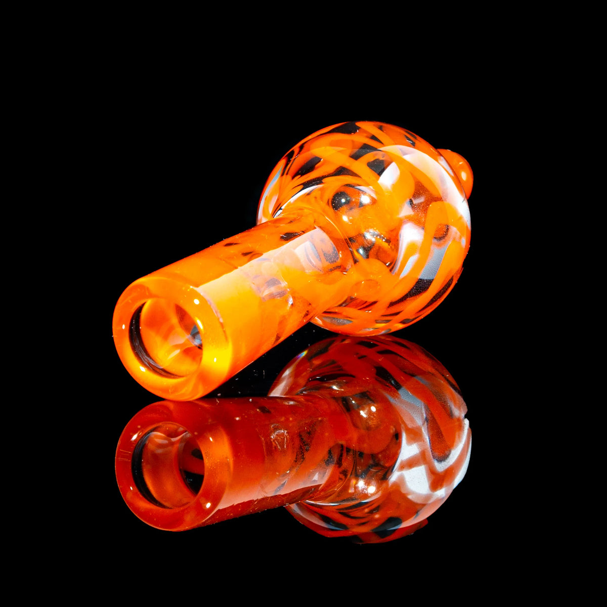 Orange glass hand pipe with swirling patterns on black reflective surface